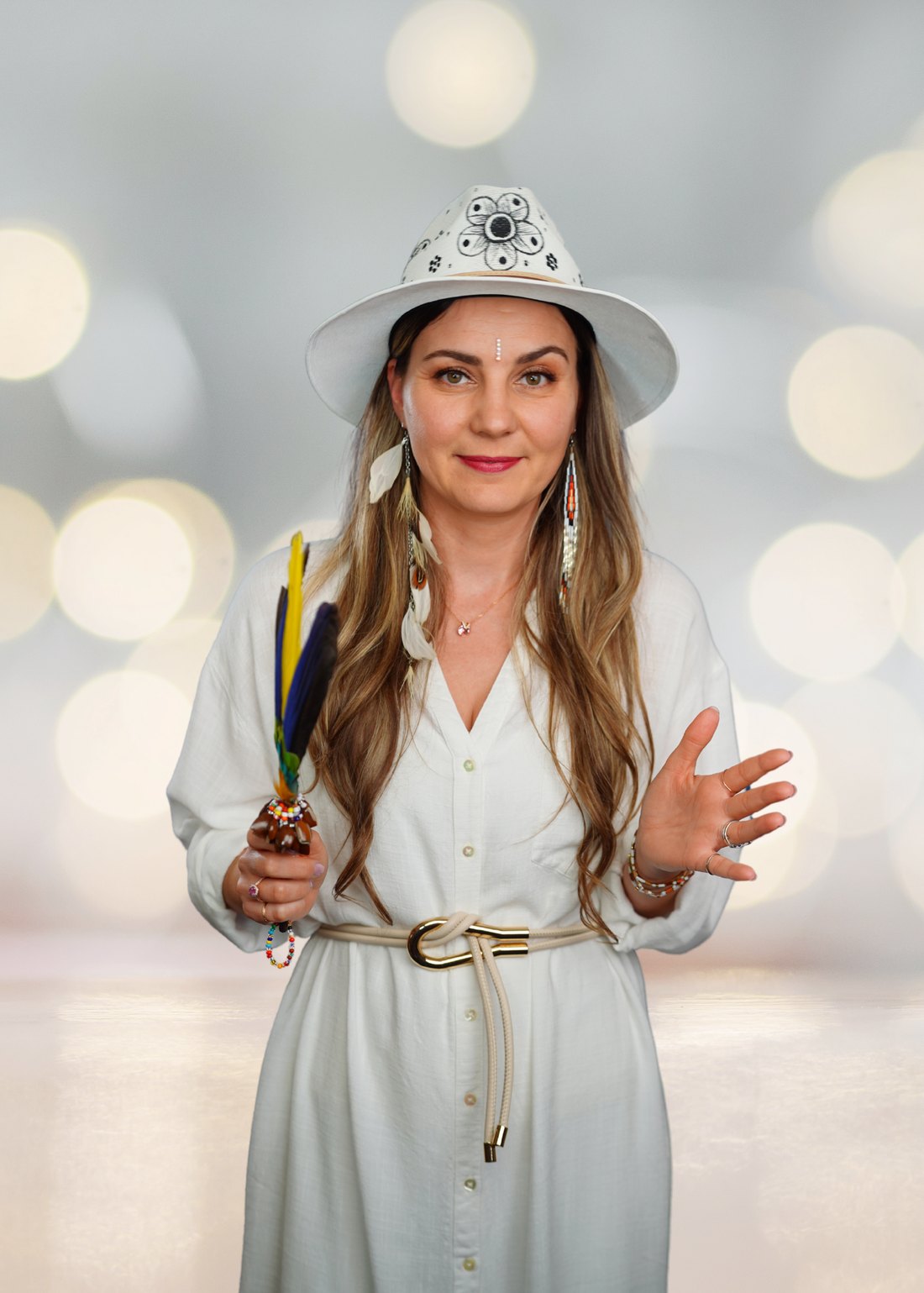 Maya, energy healer, dressed in white and holding a feather smudging fan